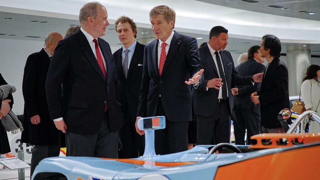 Group of men around a blue and orange Porsche car