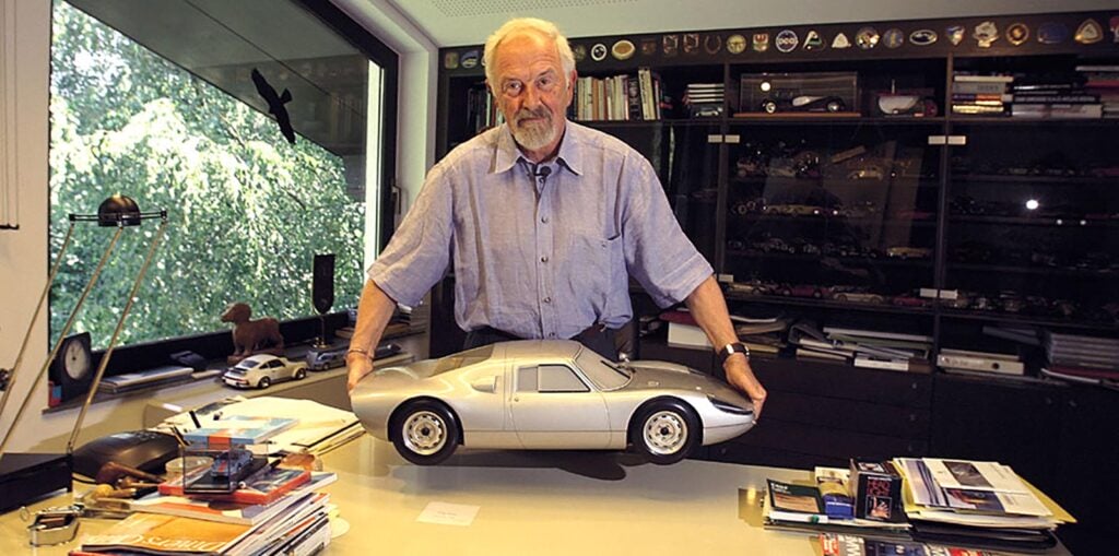 Older Ferdinand Alexander Porsche holding a Porsche 904 model