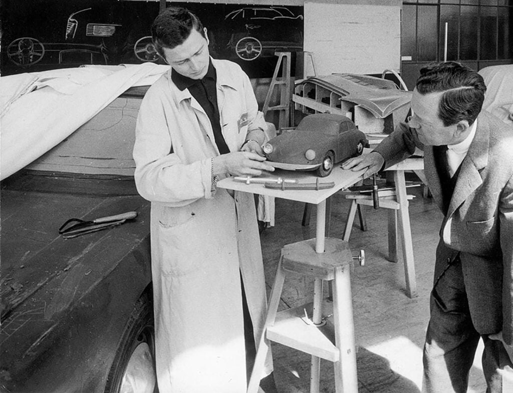 black and white photo two men looking at a model car