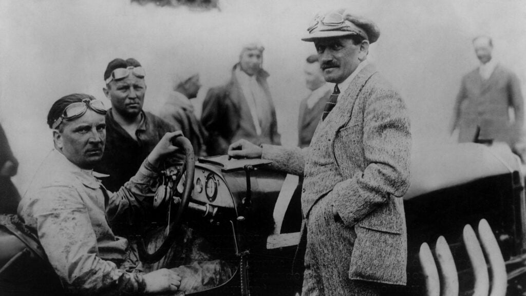 black and white photo 3 men standing next to car