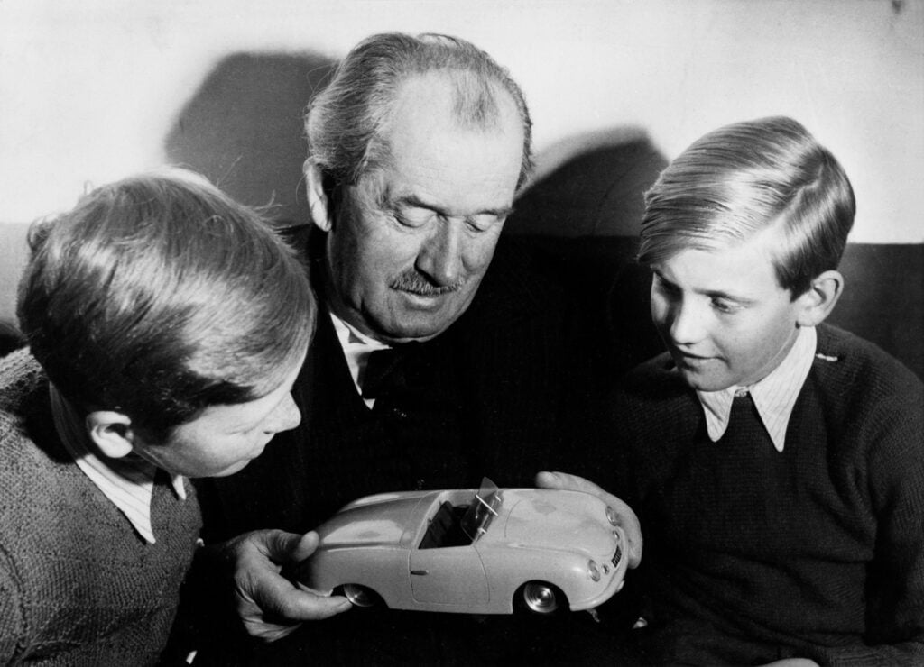 black and white photo older man with young kids looking at a toy car