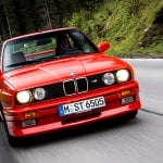 red BMW E30 M3 driving on winding road