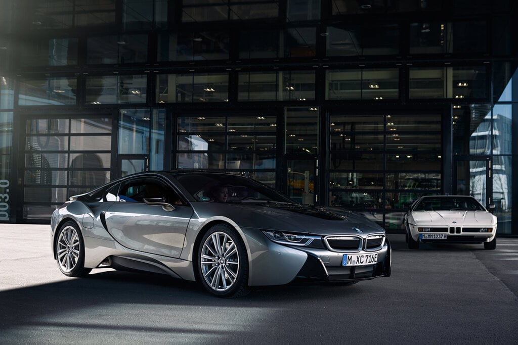 Silver BMW i8 next to white BMW on asphalt