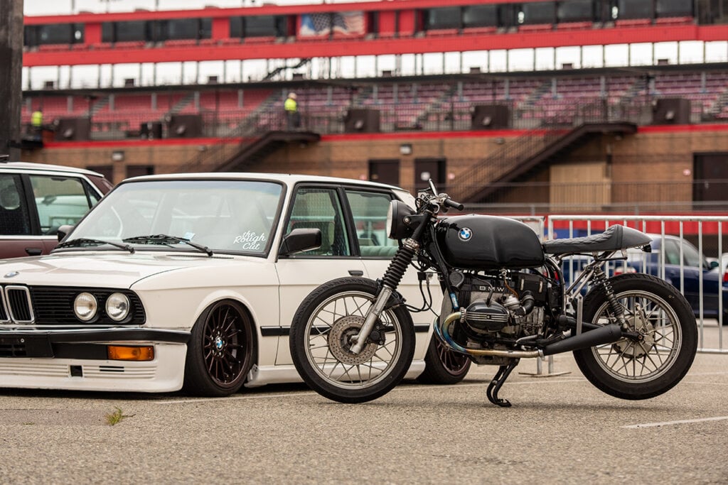 BMW motorcycle and white BMW on asphalt