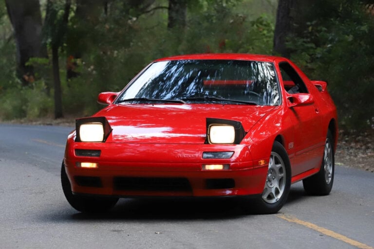 Red Mazda RX7 FC on road with trees in background