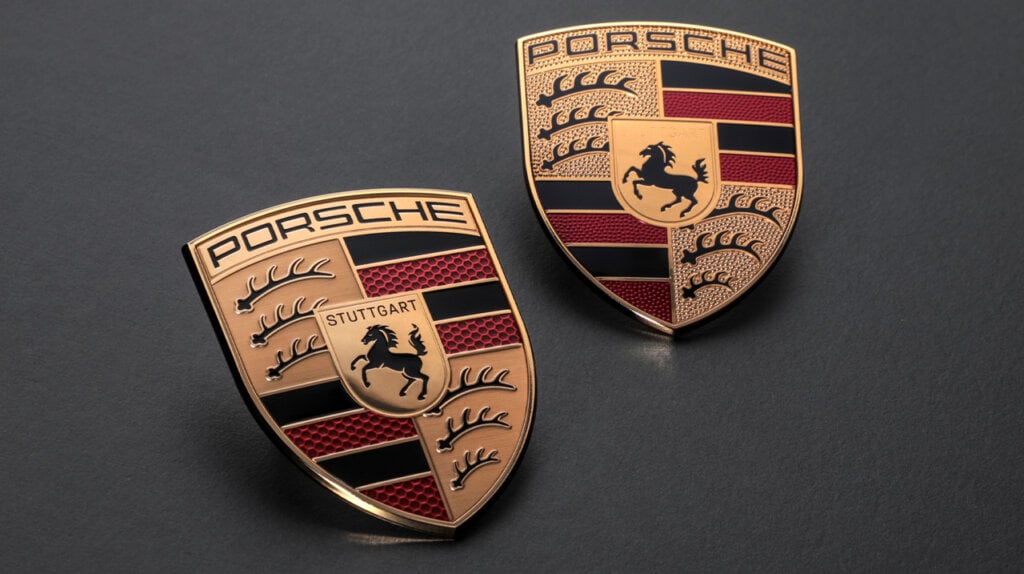 the new gold, black, and red Porsche crest next to the older crest