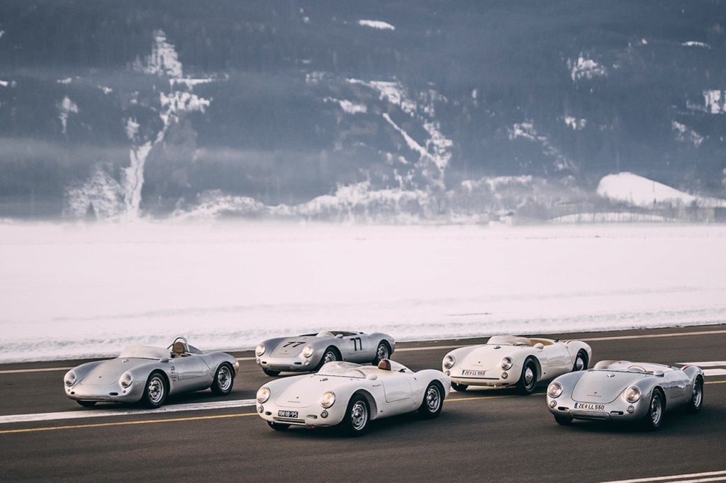 group of Porsche Spyders parked on road with icy mountains