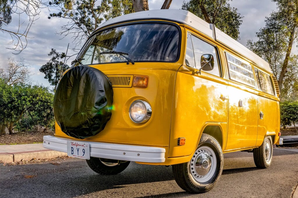 Golden yellow Westfalia T2 on the road with trees in background