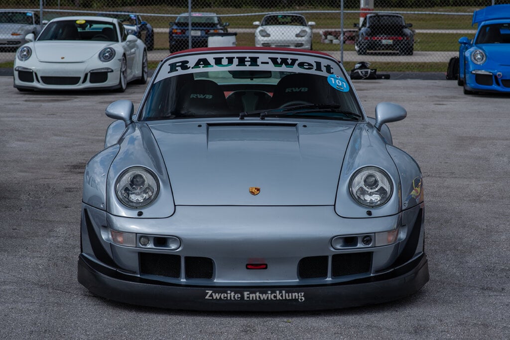 silver RWB porsche with big white banner parked in front of other Porsche cars