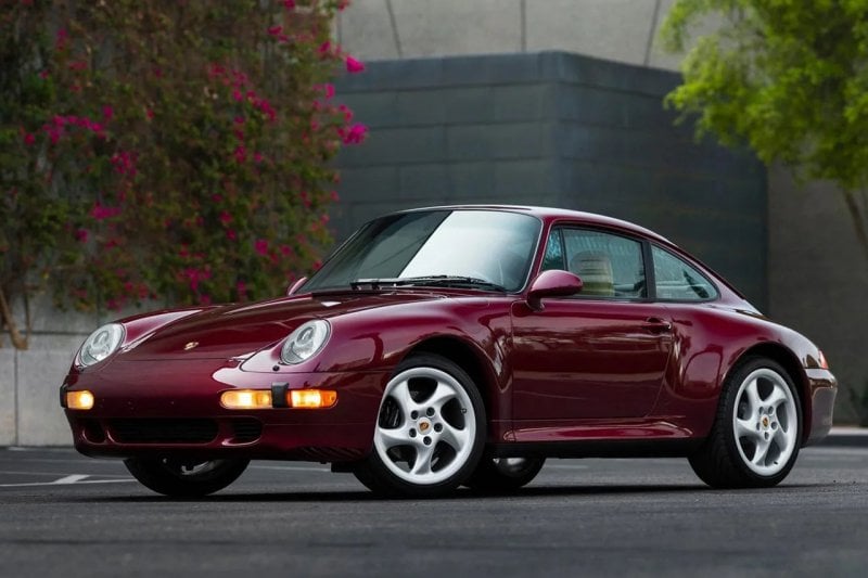 purple Porsche 993 in front of flower wall and on asphalt