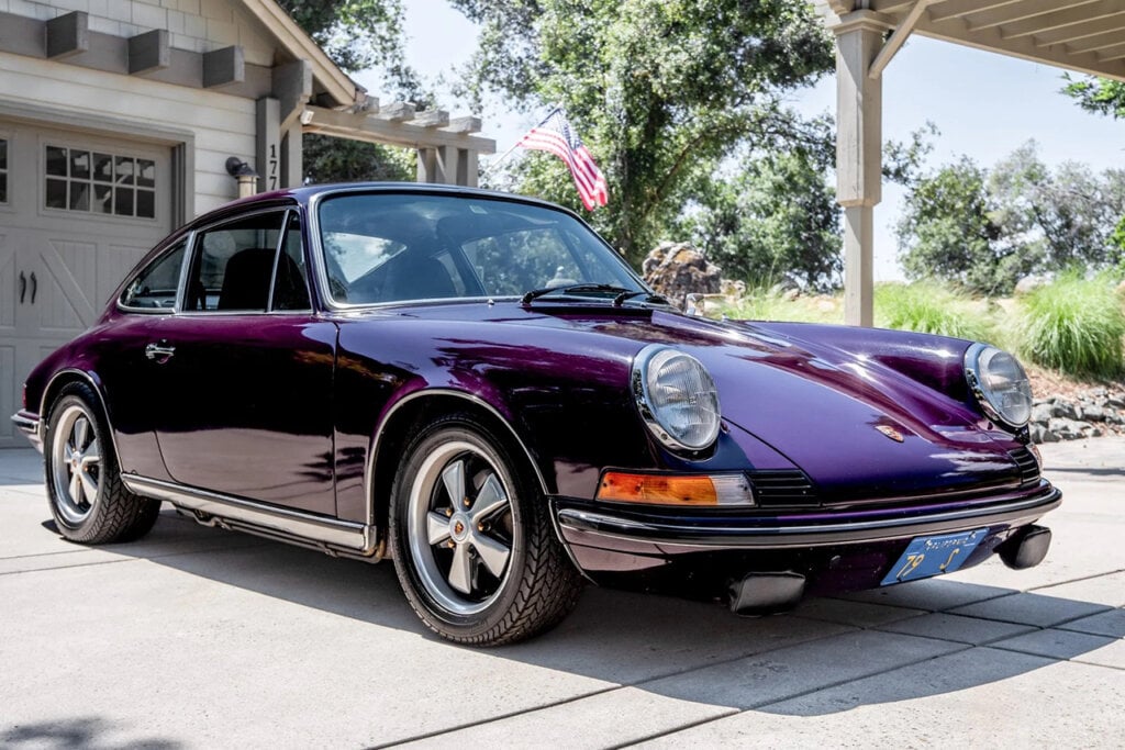 purple 911 in front of a garage with USA Flag behind it
