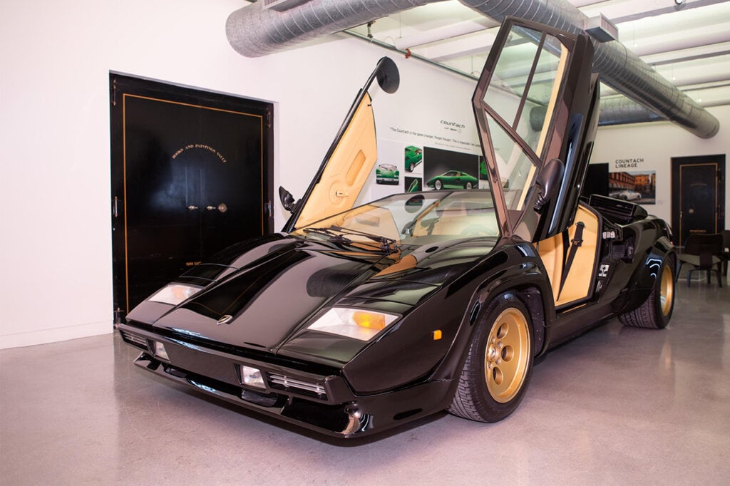 LP 5000 Quattrovalvole in a showroom, air duct above it and black doors next to the car
