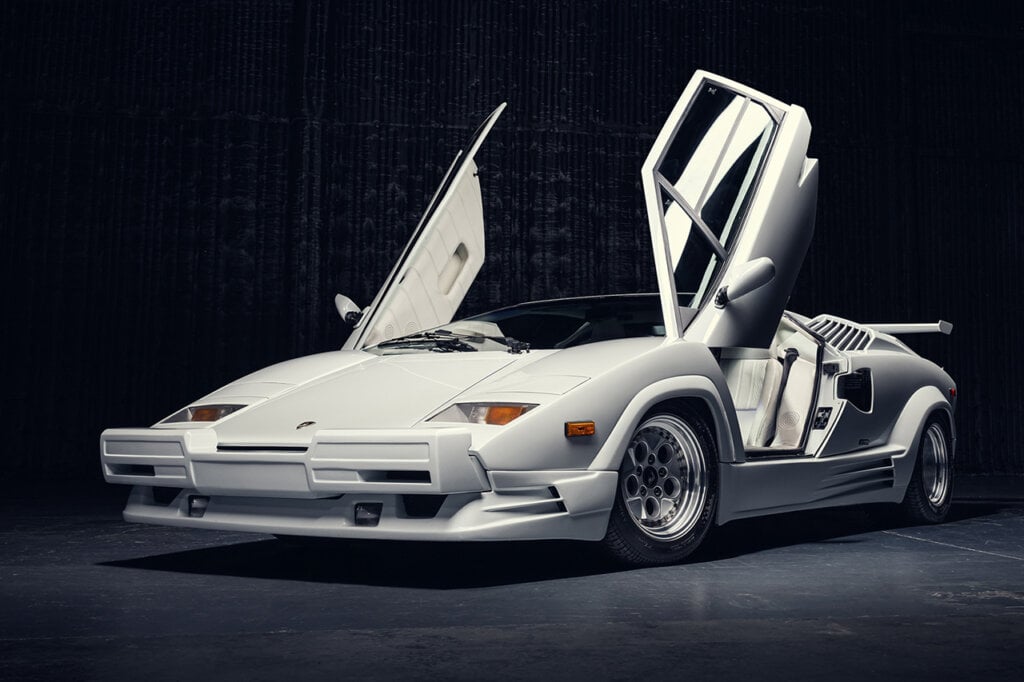 White Lambo Countach from movie Wolf of Wall Street with doors open, black background behind it.