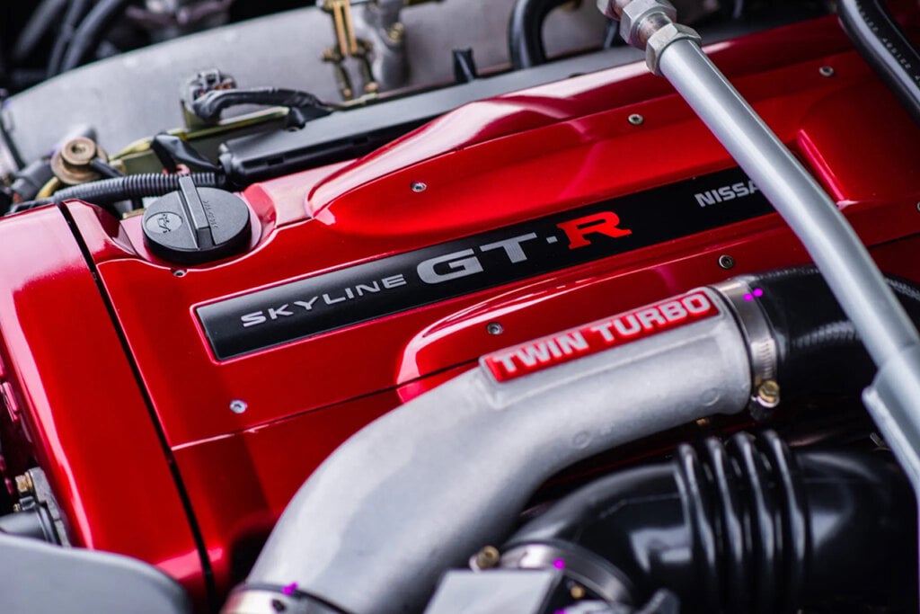Red valve cover that has writing that says Skyline GT-R with a tube going over it