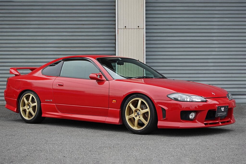 red Nissan Silvia s15 in front of some garage doors