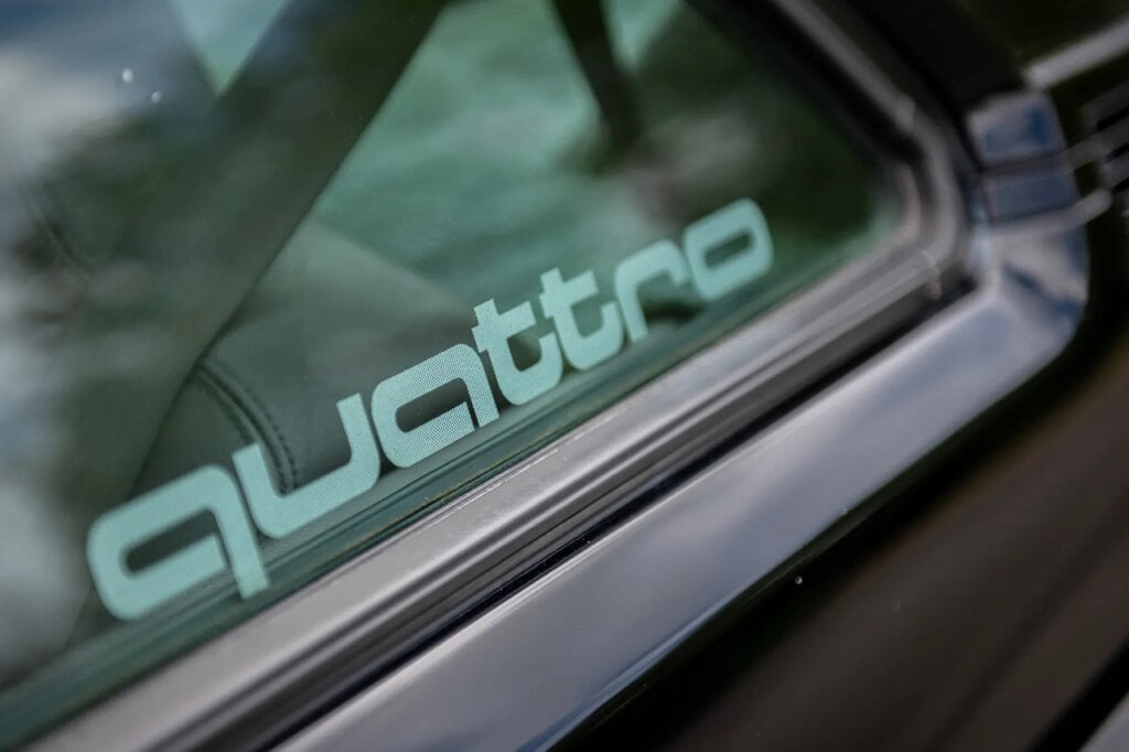 Word that says Quattro printed white on the window of a black Audi Quattro