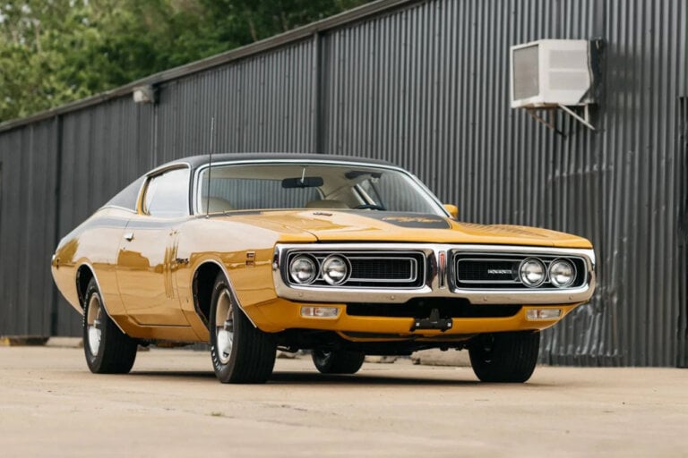 yellow with black racing stripes 1970 dodge charger parked in front of building