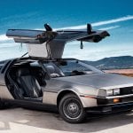 DMC Delorean with gull wing doors open and blue sky with white streak in the back