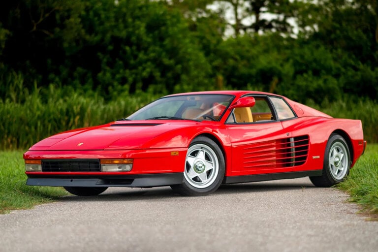 Red Ferarri Testarossa Parked diagonally on a pathway surrounded by trees