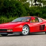 Red Ferarri Testarossa Parked diagonally on a pathway surrounded by trees