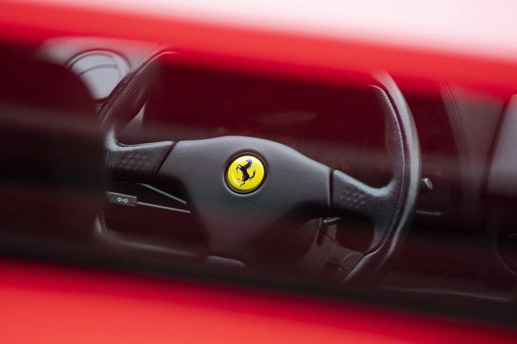 Ferrari steering wheel with two red blurry bars going over the top and bottom of the photo