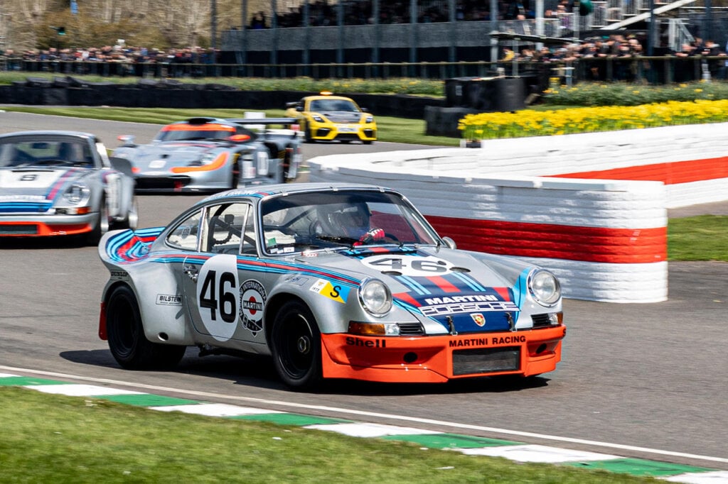 Martini Porsche race car with the number 46 on it driving ahead of other race cars on a racetrack