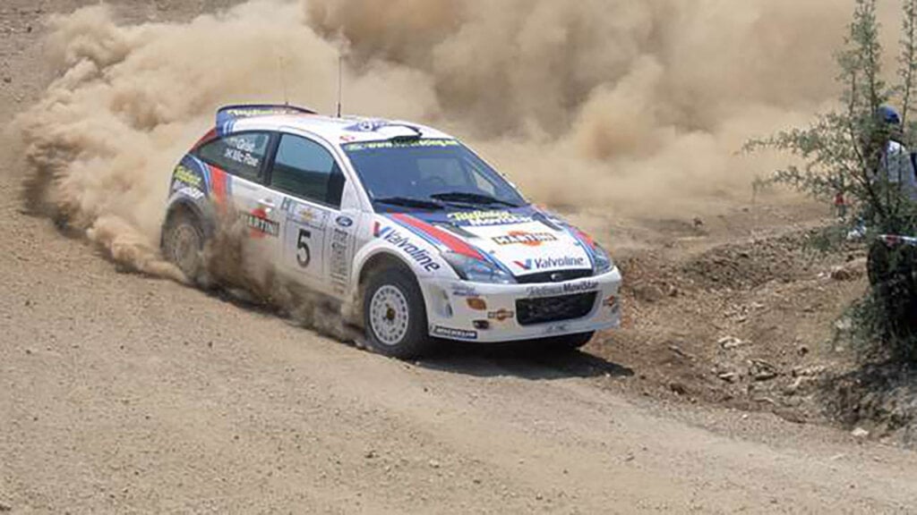white ford focus rally tuned driven by colin mcrae on a dirt road