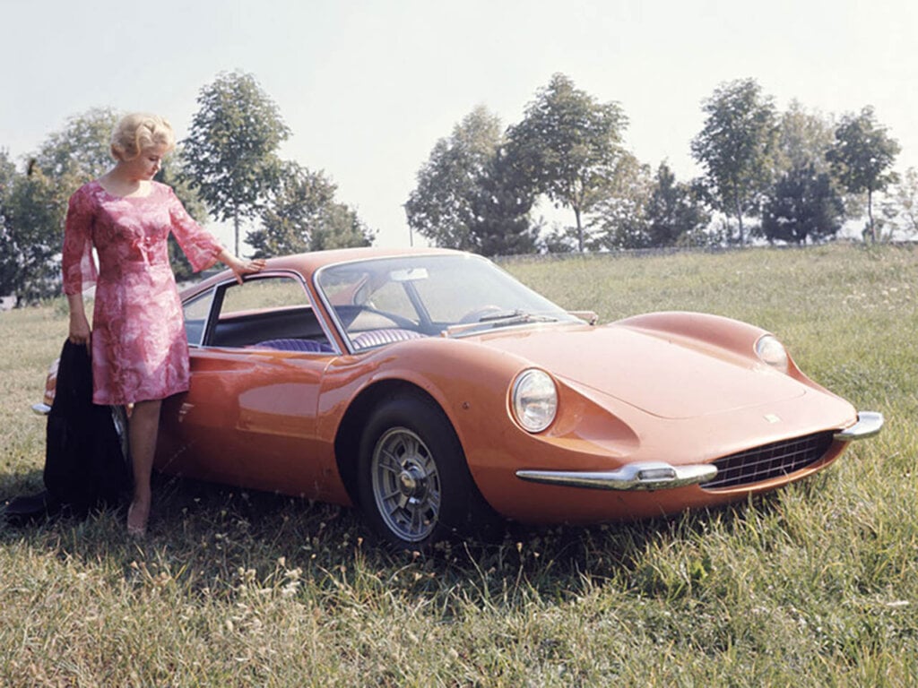 woman right next to an orange 250 GT Coupe