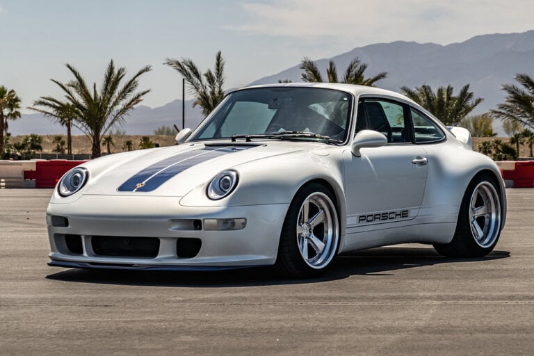 White Porsche 911 with blue racing stripes parked in a parking lot