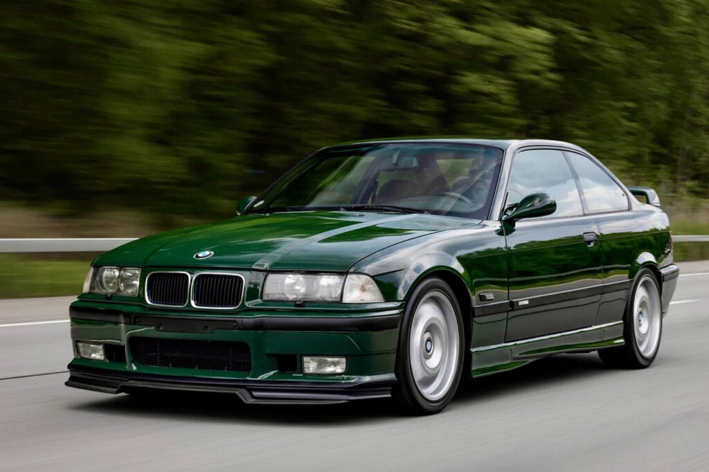 green BMW e36 M3 driving on freeway passing trees