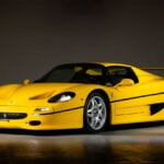 Yellow Ferrari F50 on dark background parked with lights on