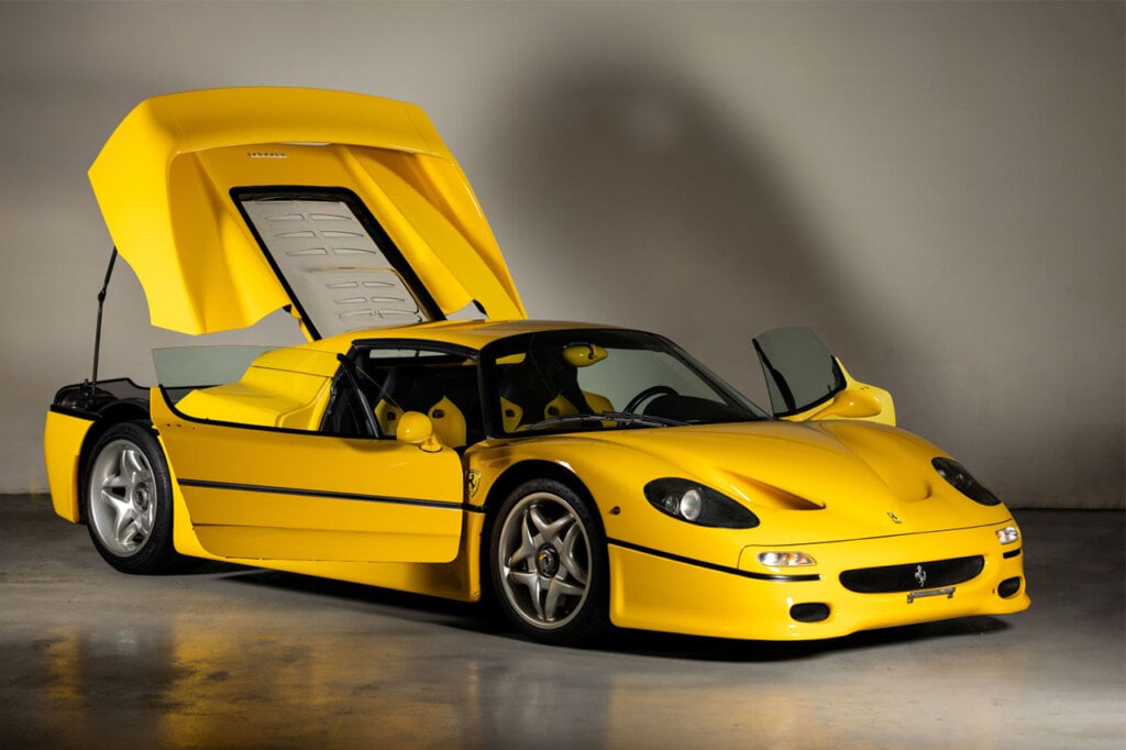 Ferrari F50 Giallo Modena with doors and trunk open parked inside of garage next to white wall with large shadow on it