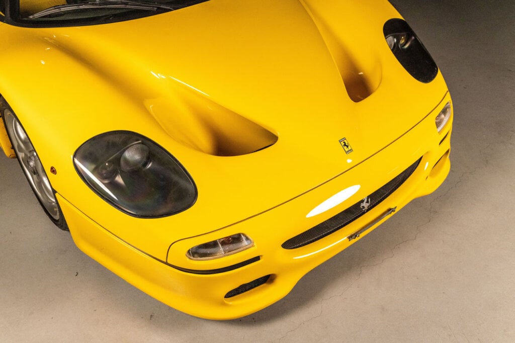 Closeup of Giallo Modena Ferrari F50, dark headlights and two large vents coming out of the front of the hood