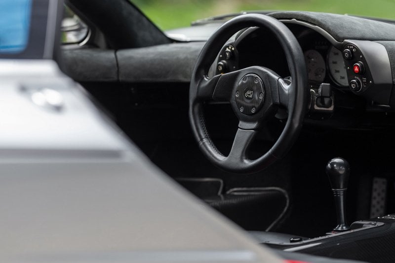 Black interior steering wheel and manual stickshift in center console of a grey McLaren F1