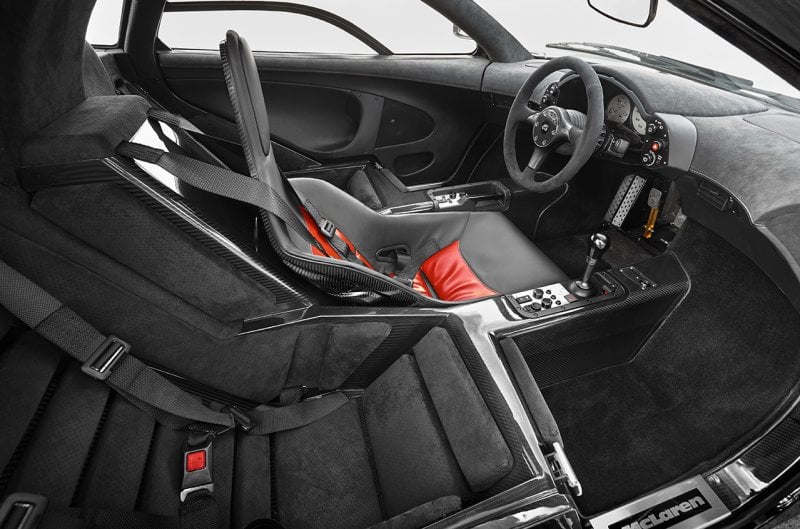 McLaren F1 black and red interior with the driver seat in the front and two on either side.