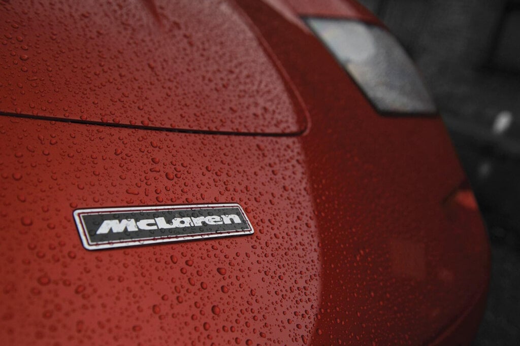 Black and white McLaren Badge on a red F1 with raindrops on it