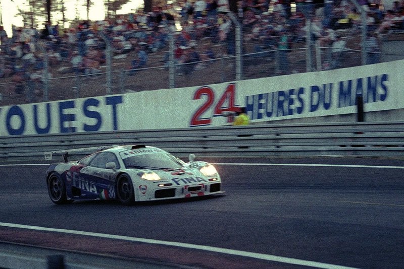 White McLaren on a racetrack with headlights on during the 1996 24hrs Le Mans