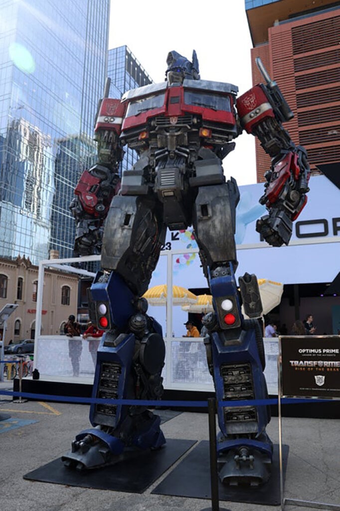 Optimus Prime statue standing up next to large city buildings