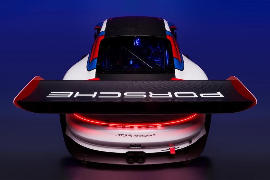 Rear side of a Porsche 911 GT3 R Rennsport edition showing the engine and the rear race inspired GT wing. The wing says Porsche on it