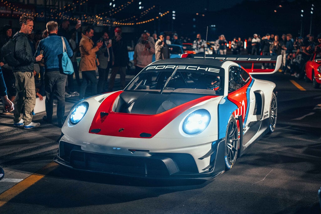 Man driving a Porsche 911 GT3 R Rennsport through a crowd at night
