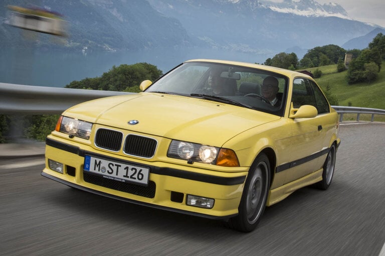 yellow e36 m3 driving on a country road