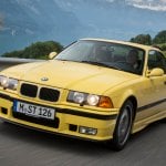 yellow e36 m3 driving on a country road