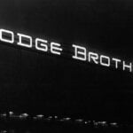 Black and white photo of a sign that says Dodge Brothers with a really dark black background