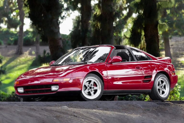 Red Toyota MR2 parked under some trees
