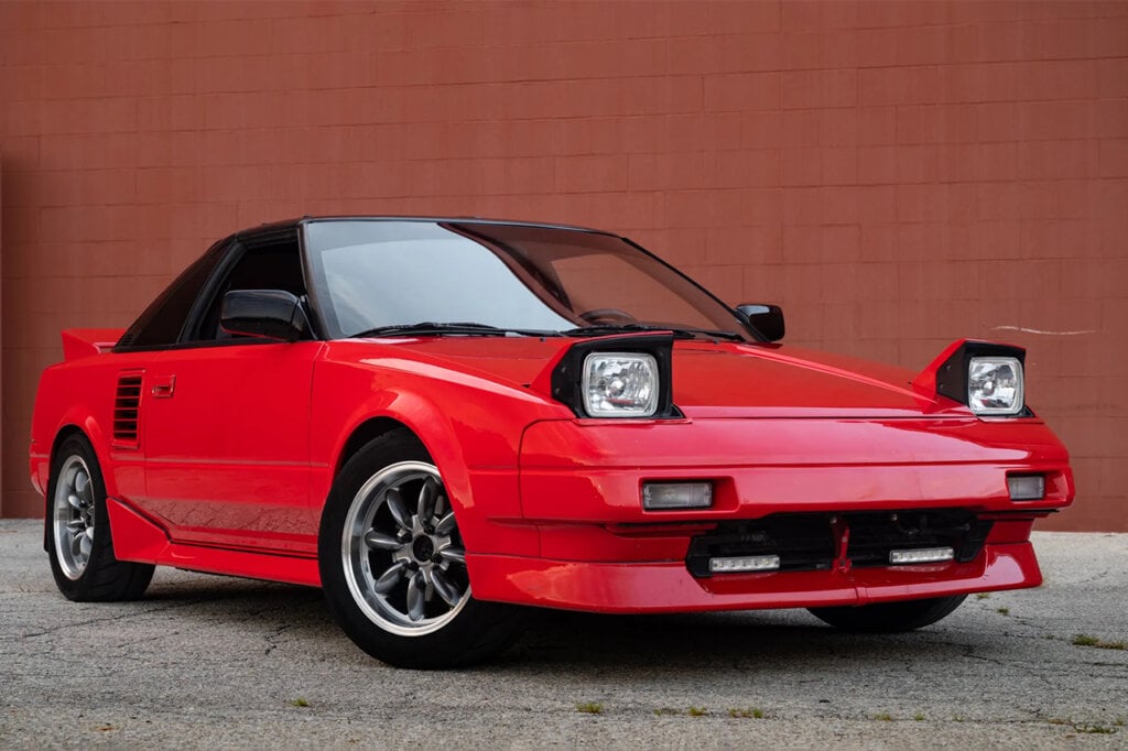 Red Toyota MR2 in front of a brick wall