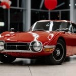 Red Toyota 2000GT displayed on the showroom floor of a Toyota dealership