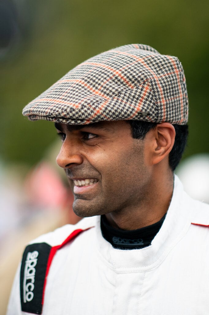 Man with a striped hat and a white racing suit smiling
