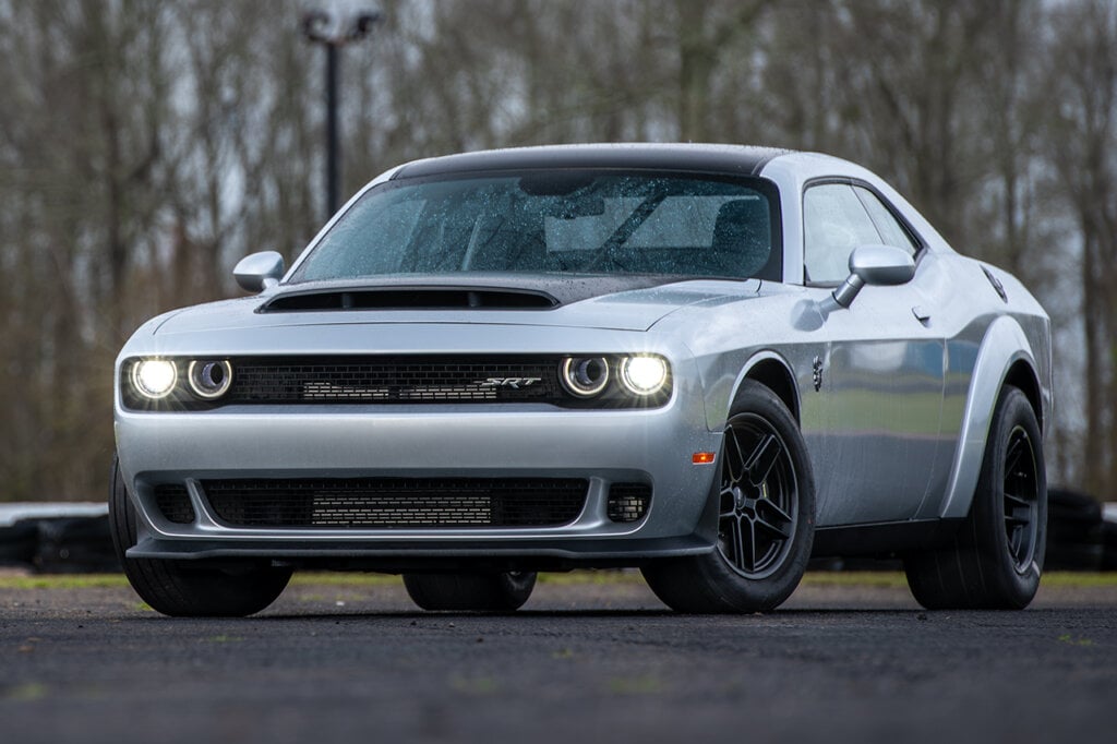 Grey Dodge Demon Challenger parked infront of some trees
