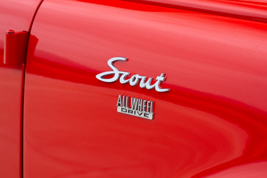 Car badge finished in chrome that says Scout All Wheel Drive on a red door