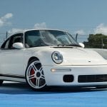 White Porsche RUF SCR parked on a blue floor with blue sky with clouds in background